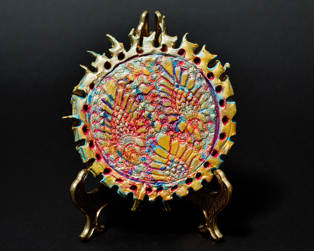 Ceramic interpretation of a flattened coronavirus, on a stand